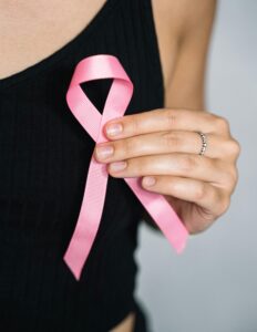 Close-up of a woman holding a pink ribbon for breast cancer awareness.